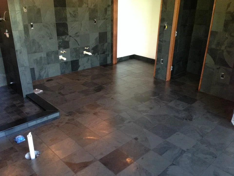 Slate tile bathroom with mixed gray and charcoal tiles on walls and floor, chrome fixtures installed
